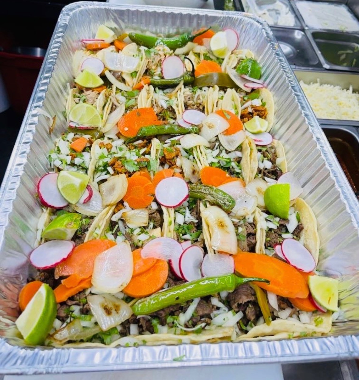Large party tray of tacos with charred peppers, carrots, radish, and lime